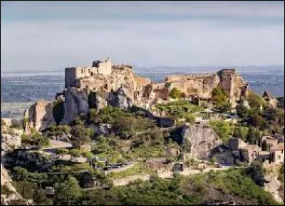 Quel est ce village, important lieu touristique de la région, situé sur un éperon rocheux du massif des Alpilles ?