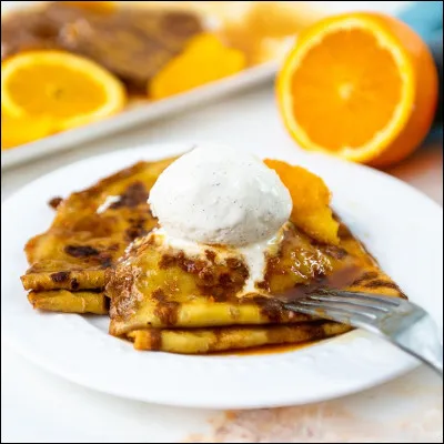 Une crêpe Suzette est composé d'une crêpe au beurre Suzette, une sauce à base de sucre caramélisé et de beurre, de jus de citron , de zeste et du Martini.