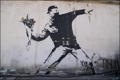 Un tagueur - Qui a r&eacute;alis&eacute; ce graffiti montrant un manifestant sur le point de lancer un bouquet de fleurs ?
