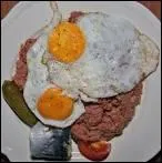 Quel est ce plat de viande de boeuf cuite  l'eau, hache et mlange  de la pure de pommes de terre, servi avec des oeufs sur le plat, des cornichons aigre-doux, des harengs ou des betteraves ?