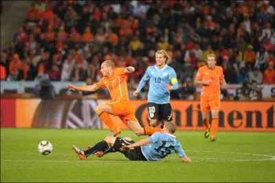 Qui est ce joueur au maillot orange esquivant un tacle ?