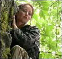 Traquée par un groupe de poursuivants, Katniss se réfugie en haut d'un arbre. De quelle manière arrive-t-elle à faire fuir la bande de tueurs ?