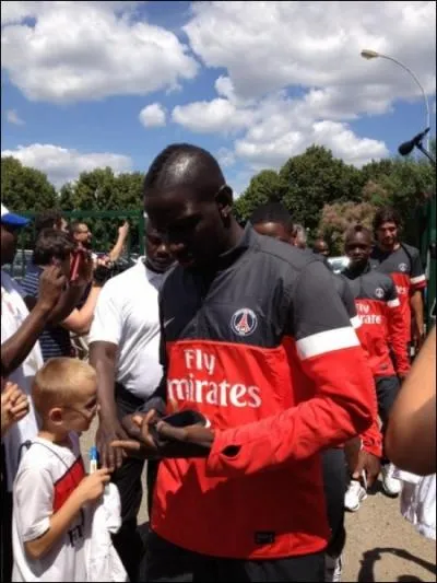 Qui est au premier plan en train de signer un autographe ?