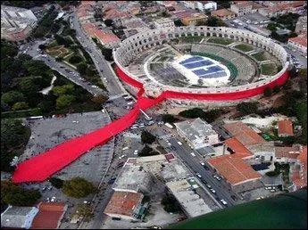 Sur cette illustration, on voit la plus grande cravate du monde, noue autour des arnes de Pula. En quel lieu, patrie de la cravate, cela s'est-il pass ?