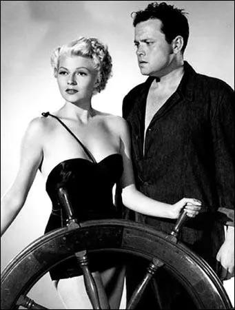En maillot de bain noir trs lgant, c'est Rita Hayworth, et prs d'elle, son mari et ralisateur Orson Welles. Quel est ce chef d'oeuvre, qu'Orson a ralis  partir d'un roman de gare ?