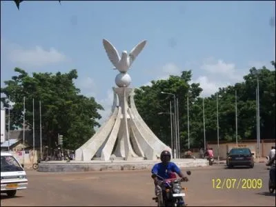 Appel  Carrefour de la Colombe de la Paix , il est situ sur un rond-point reliant les quatre grands axes de la capitale. L'oiseau perch sur un globe, tient en son bec un brin de laurier. On est  :