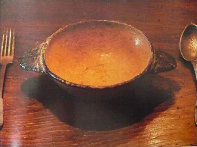 Une cuelle en terre cuite encadre de couverts d'tain. lment basique de la vaisselle paysanne jusqu' la fin du XIXe sicle. Quelle est sa caractristique ?