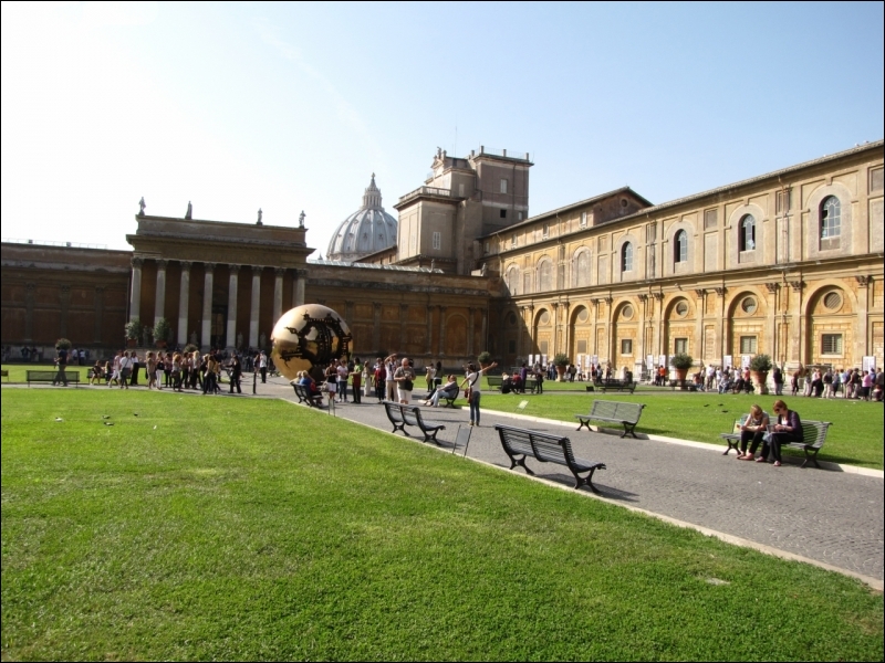 Quel objet placé dans la niche du Palais du Belvédère se trouve dans la cour de la Pigna au Vatican ?