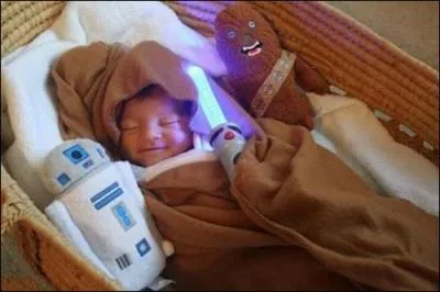 En voil un ou une qui dmarre trs tt dans la passion Star Wars ! Tout l'quipement est l, du robot au sabre laser. La tenue du bb, drap dans sa couverture marron, rappelle quel personnage de la saga ?
