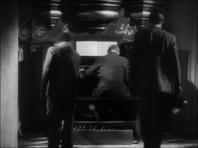 Dans le mme film, quel objet appartenant  l'assassin les hros dcouvrent-ils dans la main de l'organiste victime d'un meurtre ?