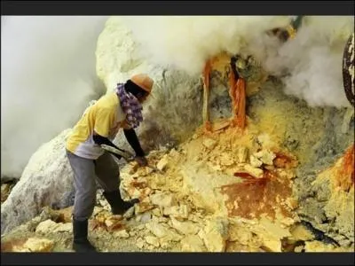 A Java c'est au travers de fumes ... que des hommes extraient des blocs de soufre dans le cratre du volcan Kawah Idjen.