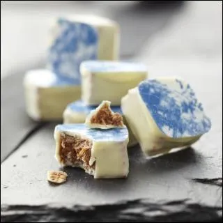 Faux petit carreau de faïence bleu, ce praliné aux épices, enrobé de chocolat blanc moiré de bleu, est la 'Faïencine du ...', en Franche-Comté !
