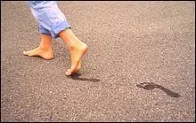 Lucas marche nu-... sur la plage, laissant des empreintes dans le sable.