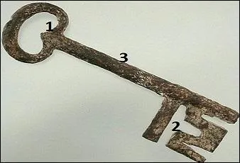 Où se trouve le panneton de cette clé en fer forgé ?