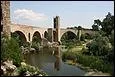 Ce pont de huit arches fortifié, enjambe le rio Fluvia. Il a été construit au XIIe siècle en Catalogne à :