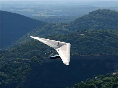 Le pilote d'un deltaplane est assis dans un harnais fixé au milieu de l'aile en forme de delta.