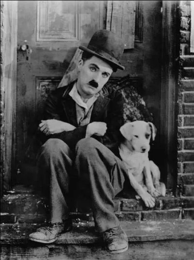 Complétez la tenue vestimentaire de Charlot, personnage de fiction interprété par I'icône du cinéma muet, Charlie Chaplin. Pantalon flottant et tombant, redingote noire étriquée sur un veston boutonné, chaussures trop grandes, canne souple en bambou et...