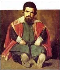 Quel est l'empereur romain qui, pendant les spectacles de gladiateurs, avait assis à ses pieds un nain vêtu d'écarlate et dont la tête était difforme ?