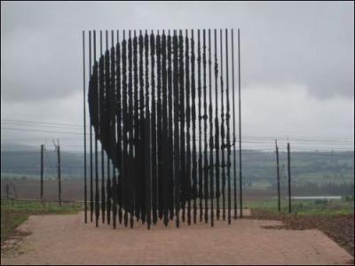 Voir la photo ci-dessus.
Ce monument se trouve en Afrique du Sud. Il est constitué de cinquante barres d'acier sculptées par Cianfanelli. 
Si vous vous placez au bon endroit vous pouvez voir, par un jeu de lumière, le portrait de ... .