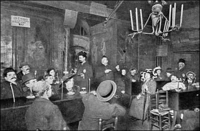 Puis, le vivant est accueilli dans l'entrée, décorée de tibias, de fémurs et de crânes, par des croque-morts au costume noir et au visage blanc. : "Vivez si m'en croyez, n'attendez à demain, cueillez dès aujourd'hui les roses de la vie..." sont ses paroles. De là, il passe à....