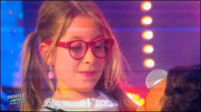 C'est la plus petite du groupe, née le 27 avril 2007. C'est avec "La vie en rose" d'Édith Piaf qu'elle a accédé aux battles de "The Voice Kids 1". Il s'agit d'/de :