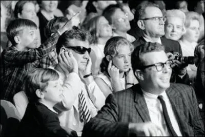 Les deux personnes qui grimacent et se bouchent les oreilles sont Leonard Bernstein (grand compositeur et chef d'orchestre, on se souvient notamment de la musique de West side story) et sa fille. Où sont-ils au moment de la photo ?